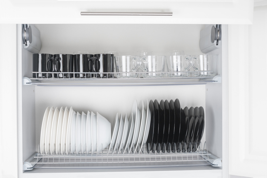 Opened kitchen cabinet with tableware close up